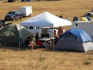 Campers relaxing under a canopy between tents